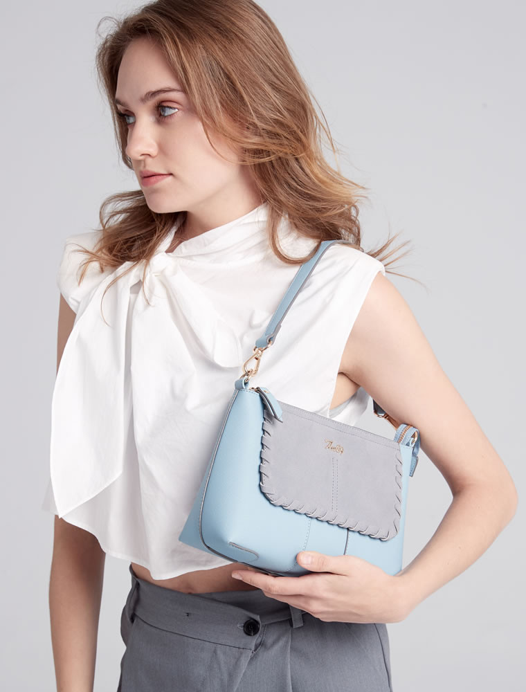 穿著白色T恤與藍色牛仔褲及白色棒球帽，斜背一個小的淺灰色斜肩包。