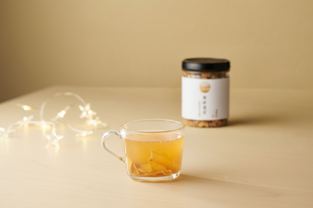 玻璃杯薑草本茶搭配茶罐與包裝盒陳列於桌面上，呈現完整商品組合與天然原料特色