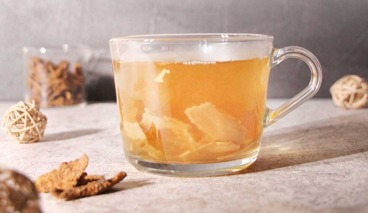透明玻璃杯中盛裝薑草本茶，可清楚看見薑片原料與自然茶色，呈現茶飲細節
