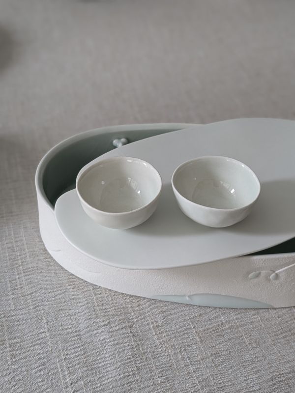 張慢 青瓷茶杯 作品多藉由輕柔小心的動作產生指向,在日常感知中搜尋相關記憶,以拆解與重組細微視角,梳理自然及現成物的輪廓與痕跡,讓他們變得輕盈自在、中性,保有更多空間自我詮釋。陶瓷僅是創作的媒材之一,無需限制於實用與非實用、工藝與藝術之間,作品的形成,即是我記錄生活的習慣與方式,人的記憶有限,瞬間記憶更是容易消散,我想將如同視覺暫留的種種,保留在生活當中。