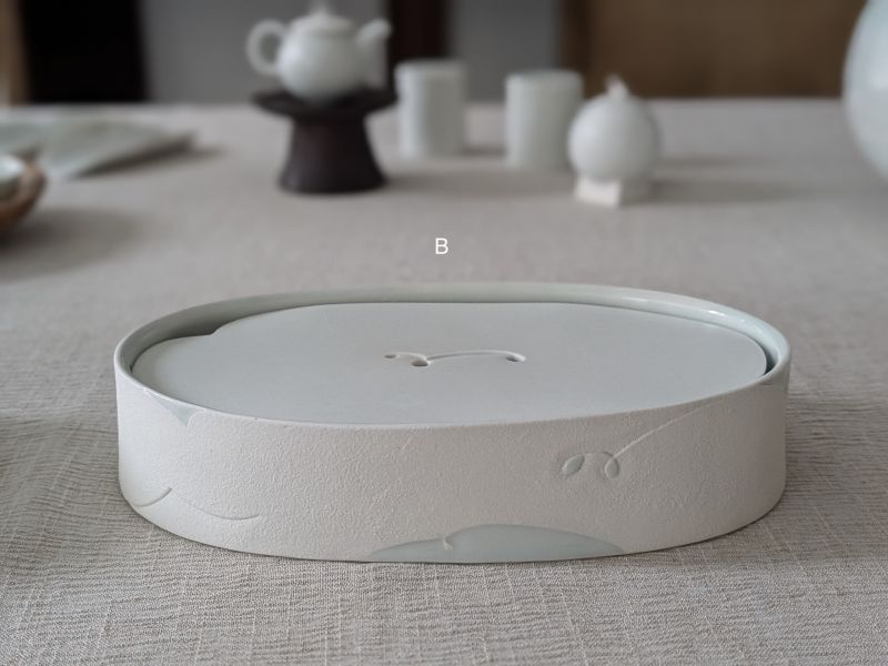 張慢 橢圓青瓷壺承/杯承(大) 作品多藉由輕柔小心的動作產生指向,在日常感知中搜尋相關記憶,以拆解與重組細微視角,梳理自然及現成物的輪廓與痕跡,讓他們變得輕盈自在、中性,保有更多空間自我詮釋。陶瓷僅是創作的媒材之一,無需限制於實用與非實用、工藝與藝術之間,作品的形成,即是我記錄生活的習慣與方式,人的記憶有限,瞬間記憶更是容易消散,我想將如同視覺暫留的種種,保留在生活當中。
