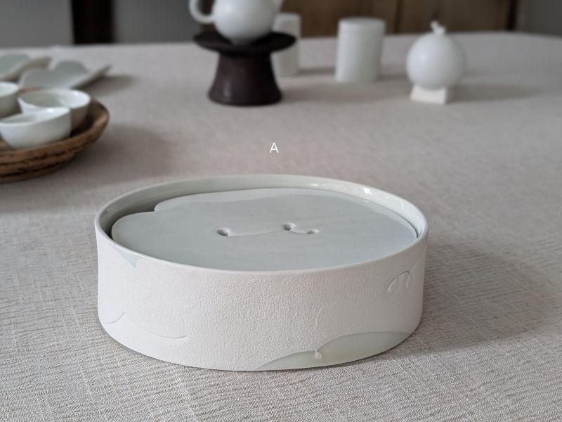 張慢 橢圓青瓷壺承/杯承 作品多藉由輕柔小心的動作產生指向,在日常感知中搜尋相關記憶,以拆解與重組細微視角,梳理自然及現成物的輪廓與痕跡,讓他們變得輕盈自在、中性,保有更多空間自我詮釋。陶瓷僅是創作的媒材之一,無需限制於實用與非實用、工藝與藝術之間,作品的形成,即是我記錄生活的習慣與方式,人的記憶有限,瞬間記憶更是容易消散,我想將如同視覺暫留的種種,保留在生活當中。
