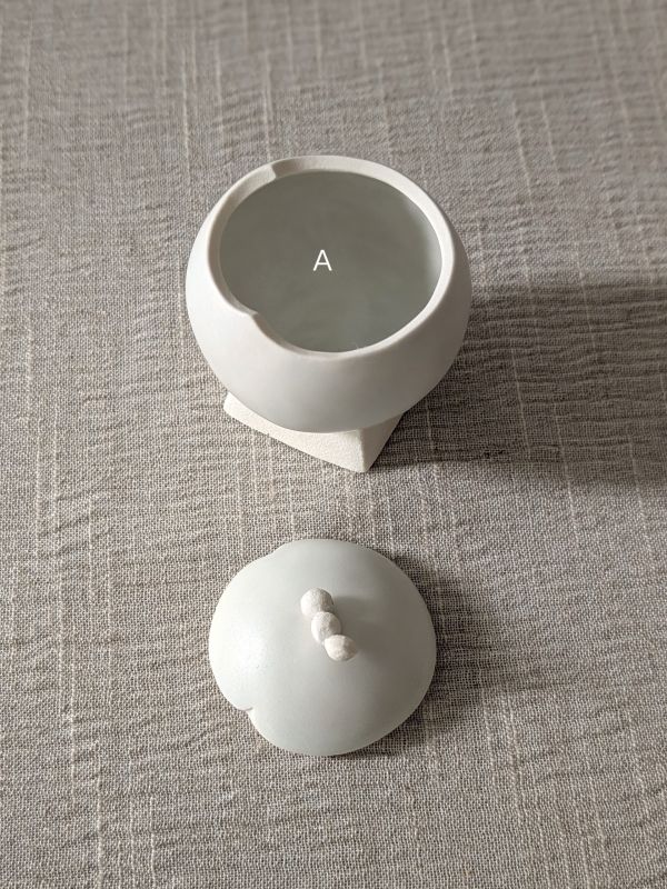 張慢 球型青白瓷茶倉(啞光) 作品多藉由輕柔小心的動作產生指向,在日常感知中搜尋相關記憶,以拆解與重組細微視角,梳理自然及現成物的輪廓與痕跡,讓他們變得輕盈自在、中性,保有更多空間自我詮釋。陶瓷僅是創作的媒材之一,無需限制於實用與非實用、工藝與藝術之間,作品的形成,即是我記錄生活的習慣與方式,人的記憶有限,瞬間記憶更是容易消散,我想將如同視覺暫留的種種,保留在生活當中。