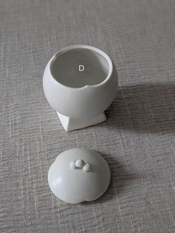 張慢 球型青白瓷茶倉(啞光) 作品多藉由輕柔小心的動作產生指向,在日常感知中搜尋相關記憶,以拆解與重組細微視角,梳理自然及現成物的輪廓與痕跡,讓他們變得輕盈自在、中性,保有更多空間自我詮釋。陶瓷僅是創作的媒材之一,無需限制於實用與非實用、工藝與藝術之間,作品的形成,即是我記錄生活的習慣與方式,人的記憶有限,瞬間記憶更是容易消散,我想將如同視覺暫留的種種,保留在生活當中。